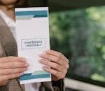 A professional holding a conference program brochure, ready for event attendees.