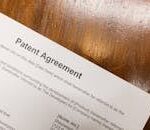 Detailed close-up of a patent agreement document on a polished wooden table.