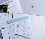 Flat lay of a tax preparation checklist, calculator, and financial documents on a desk.